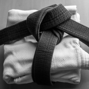 Kimono de judo plié avec une ceinture noire attachée par-dessus, prêt pour l’entraînement.