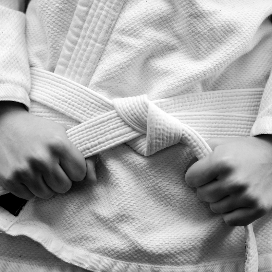Gros plan sur une ceinture de judo blanche nouée autour d’un kimono, démonstration du nœud de base.